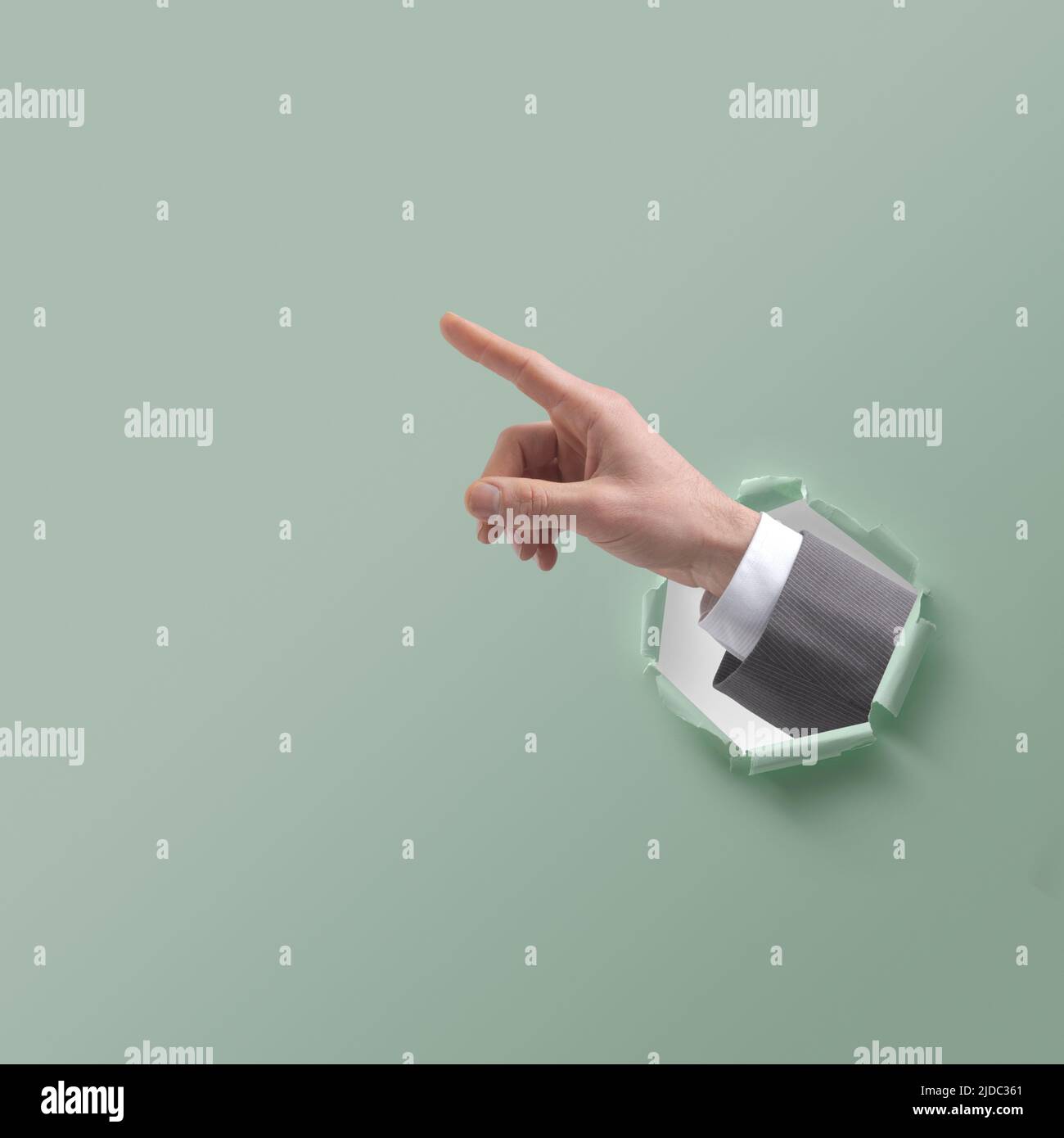 Businessman hand pointing and coming out of a hole in paper Stock Photo
