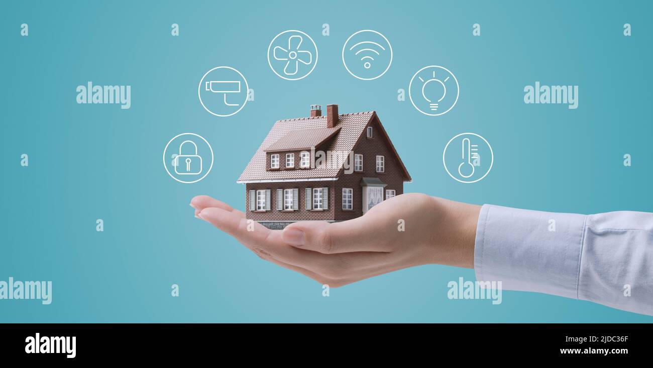 Hands holding a miniature home model with icons, smart home automation ...