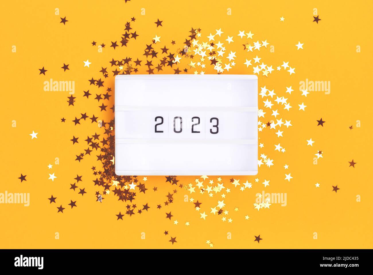New 2023 Year concept. Lightbox and golden stars confetti on a yellow background. Stock Photo