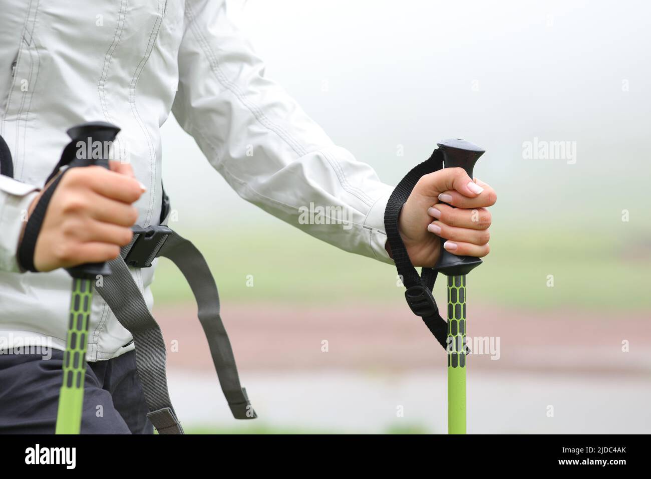 Close up of a hiker hands using poles and walking in a riverside in the mountain a foggy day Stock Photo