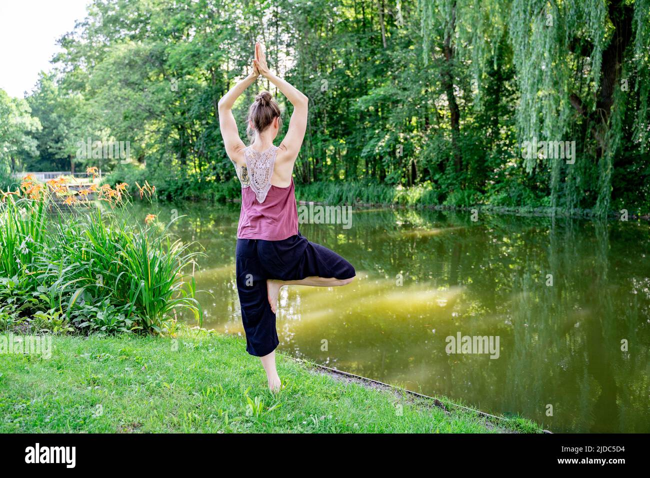 Young blond woman standing in yoga pose on one leg with hands up as in  prayer Stock Photo - Alamy
