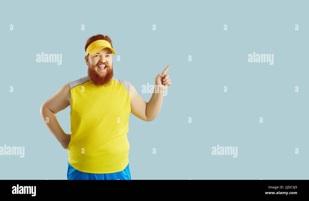 Funny happy fat man having gym workout, smiling and pointing to copy space background Stock Photo