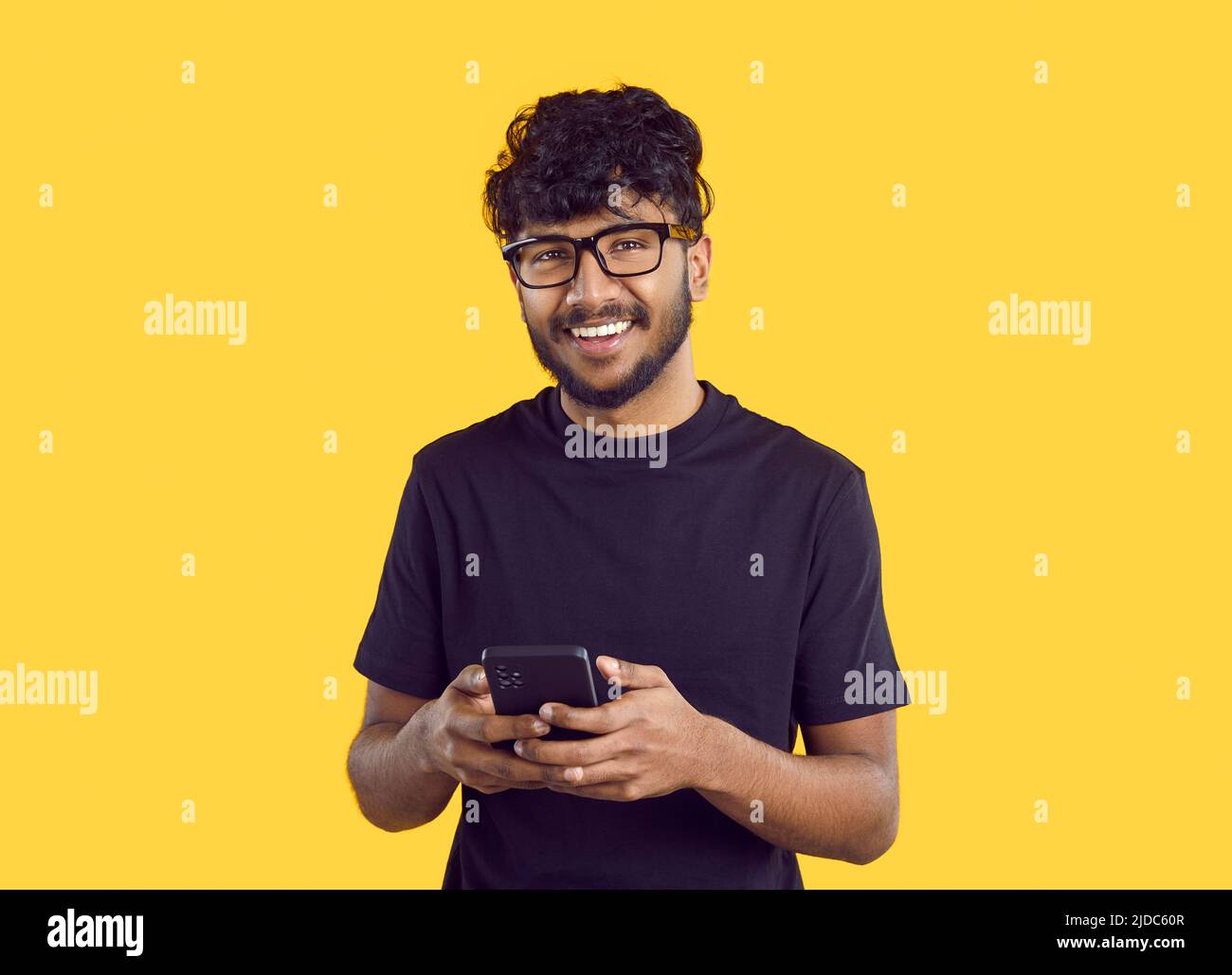 Smiling Indian man message online on cellphone Stock Photo