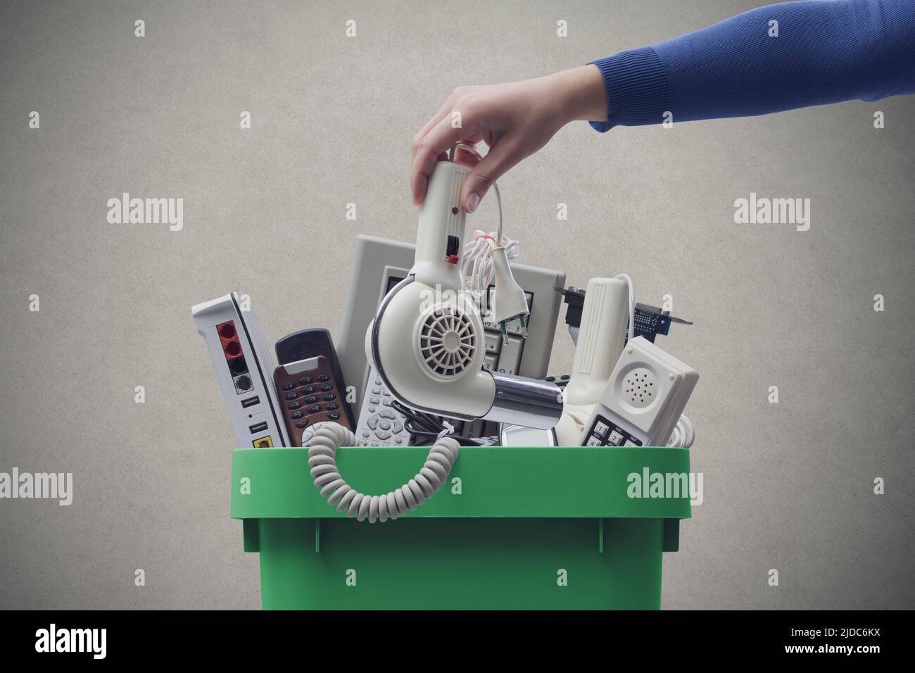 Woman putting an old broken appliance in the trash bin, ewaste and