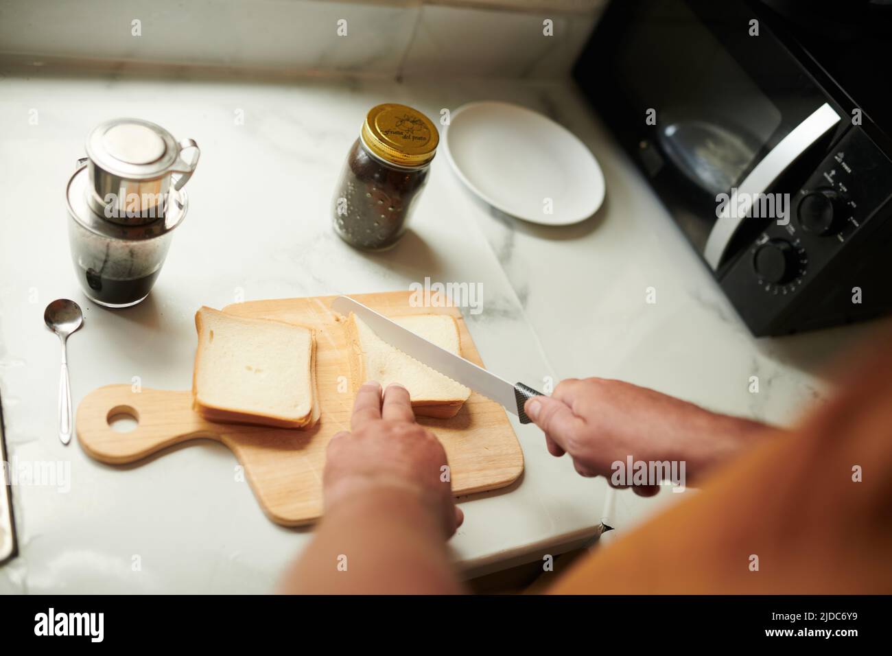 Hands of man cutting bread in triangles when making sandwiches for breakfast Stock Photo Alamy