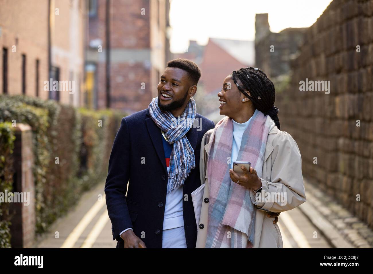Cheerful couple walking down back lane chatting and looking at buildings Stock Photo