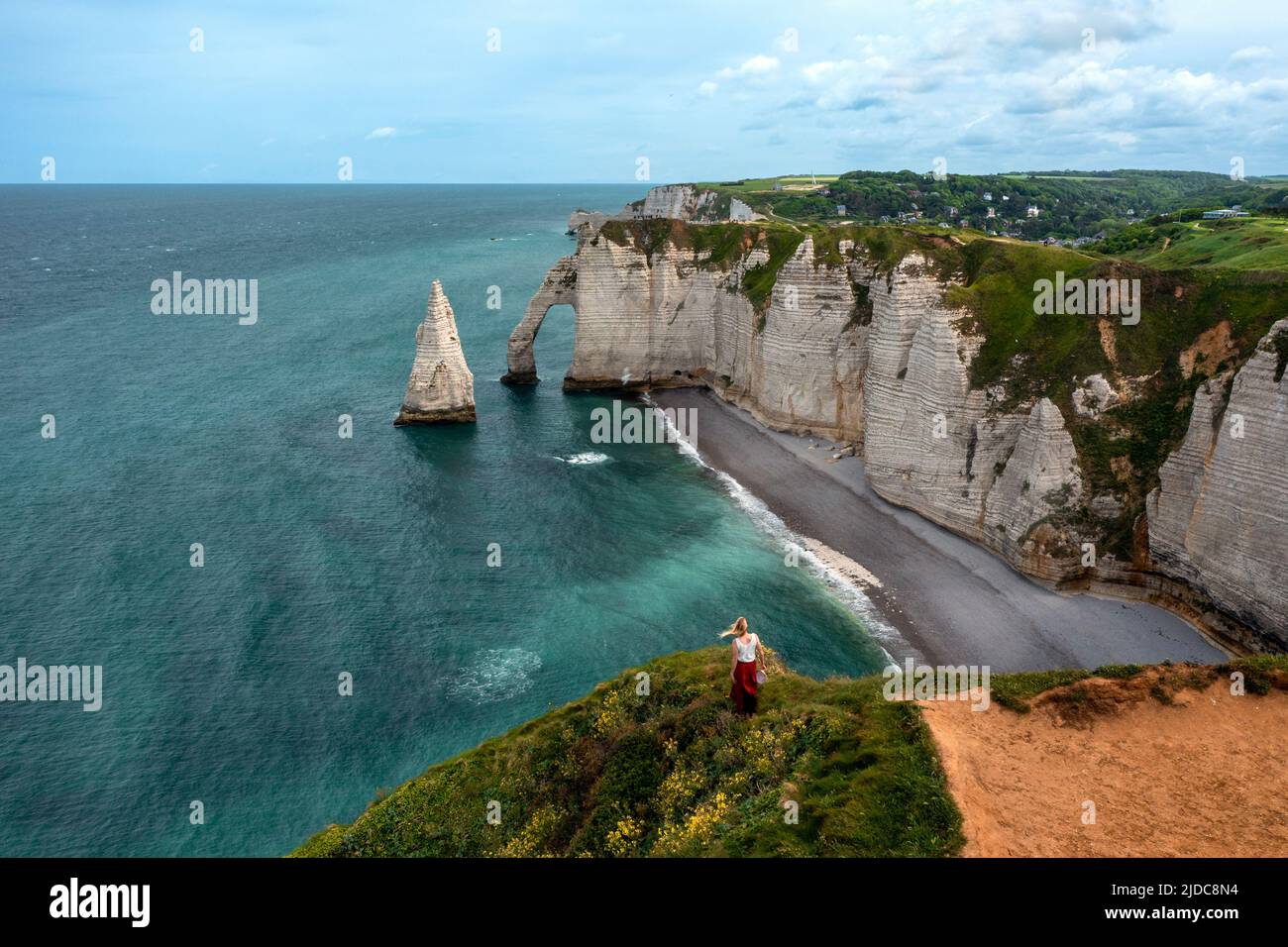 Young woman on a cliff looking at the famous Elephant White cliffs of Etretat and the Alabaster Coast, Seine-Maritime, Normandy, France Stock Photo