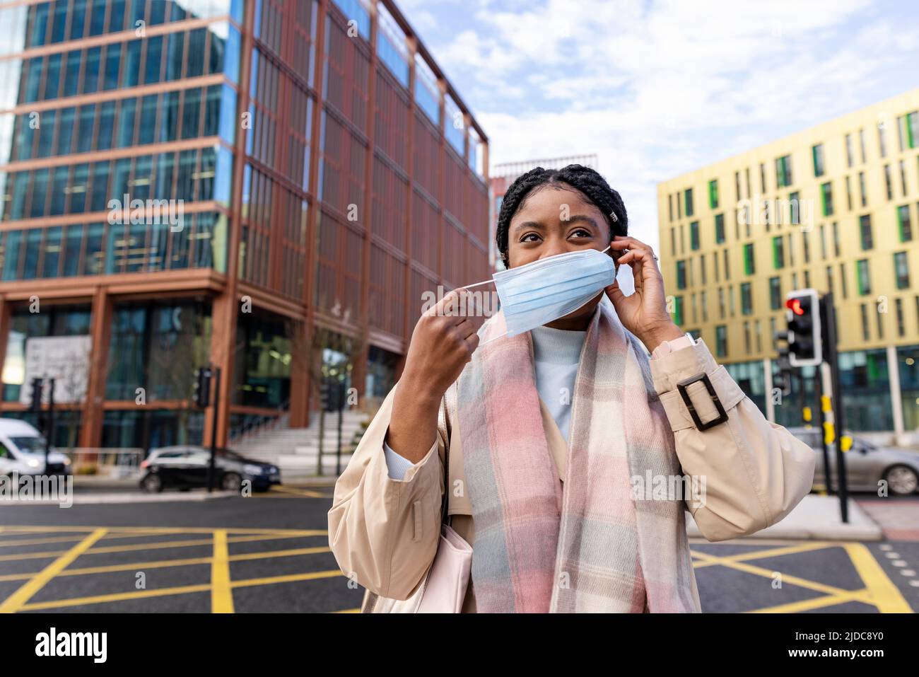 Woman holding elastic and placing face covering over nose and mouth Stock Photo