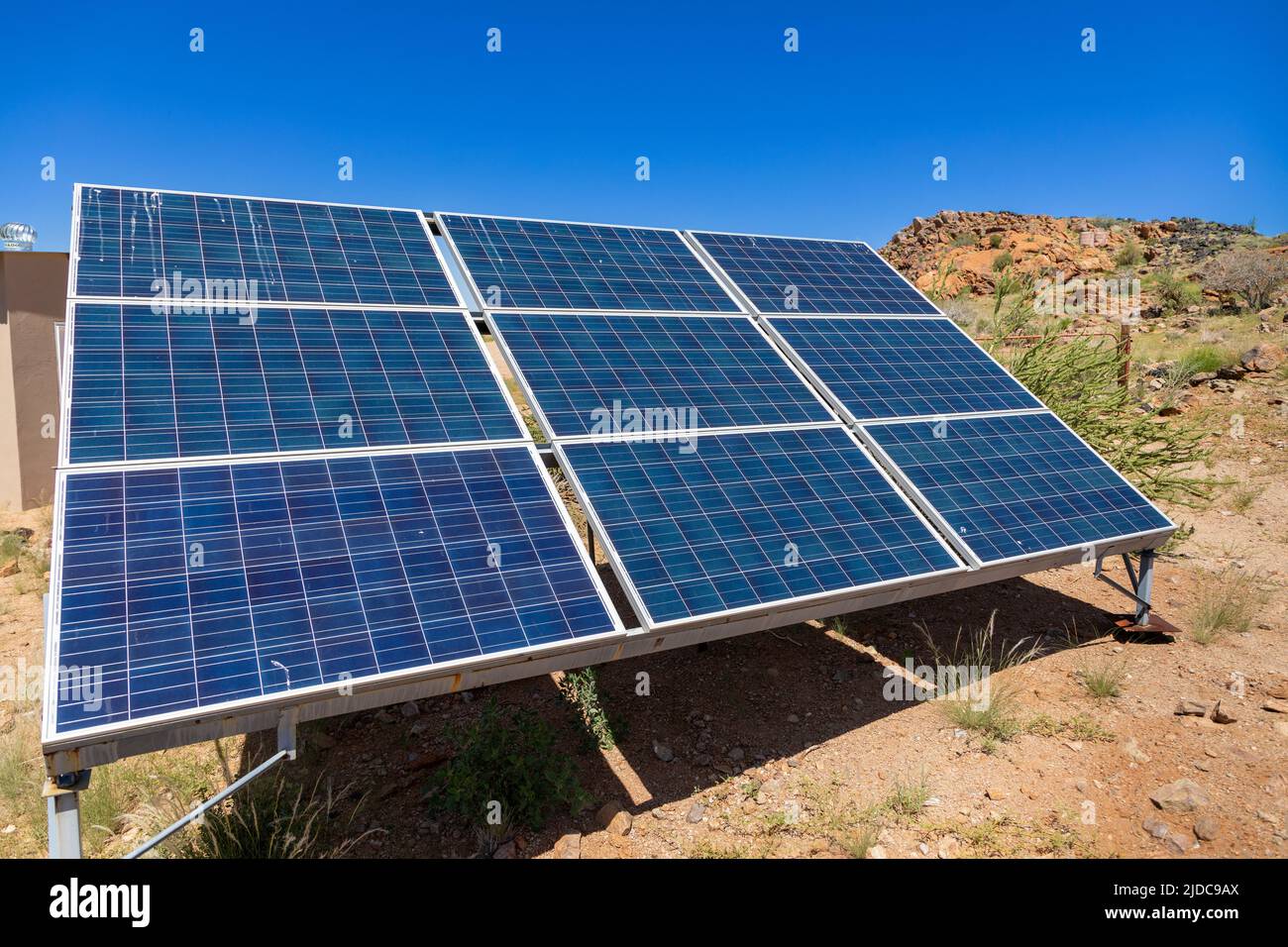 Array of nine solar panels on a custom build stand in a remote and semi dry location. No clouds in the sky. Stock Photo