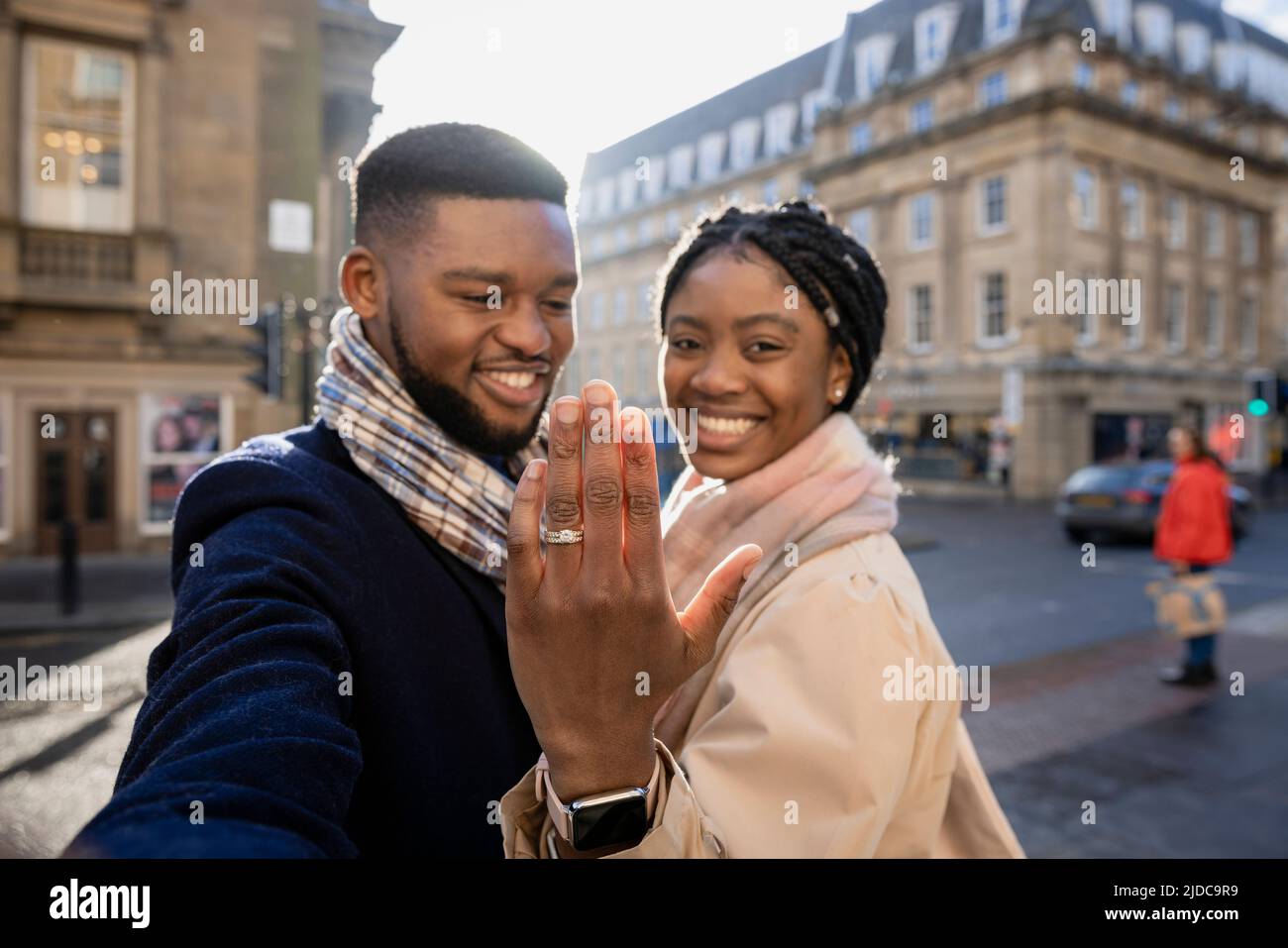 Cheerful couple in town, woman holging hand up to show engagement ring Stock Photo