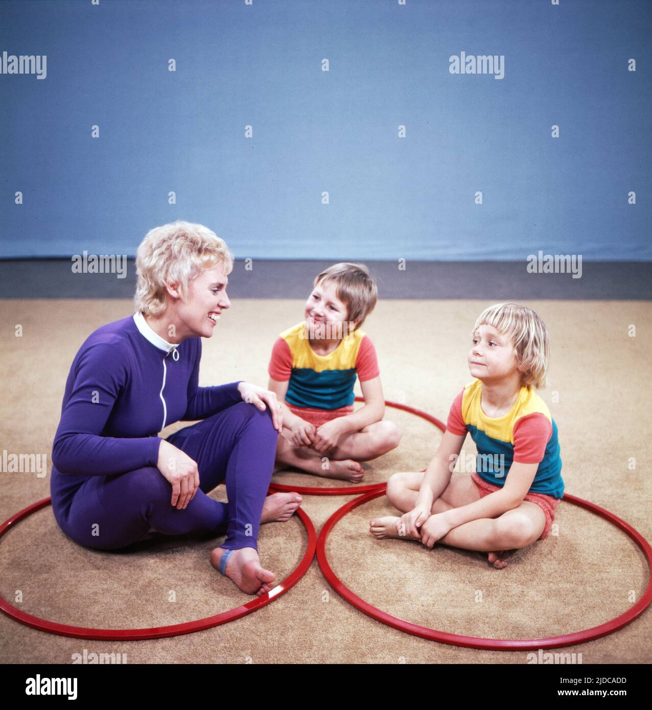 Turn mit!, Gymnastik Serie, Deutschland 1972, Vorturnerin Bärbel Vitt mit den Kindern Kathrin und Jan-Christoph turnen mit Hula Hoop Reifen Stock Photo
