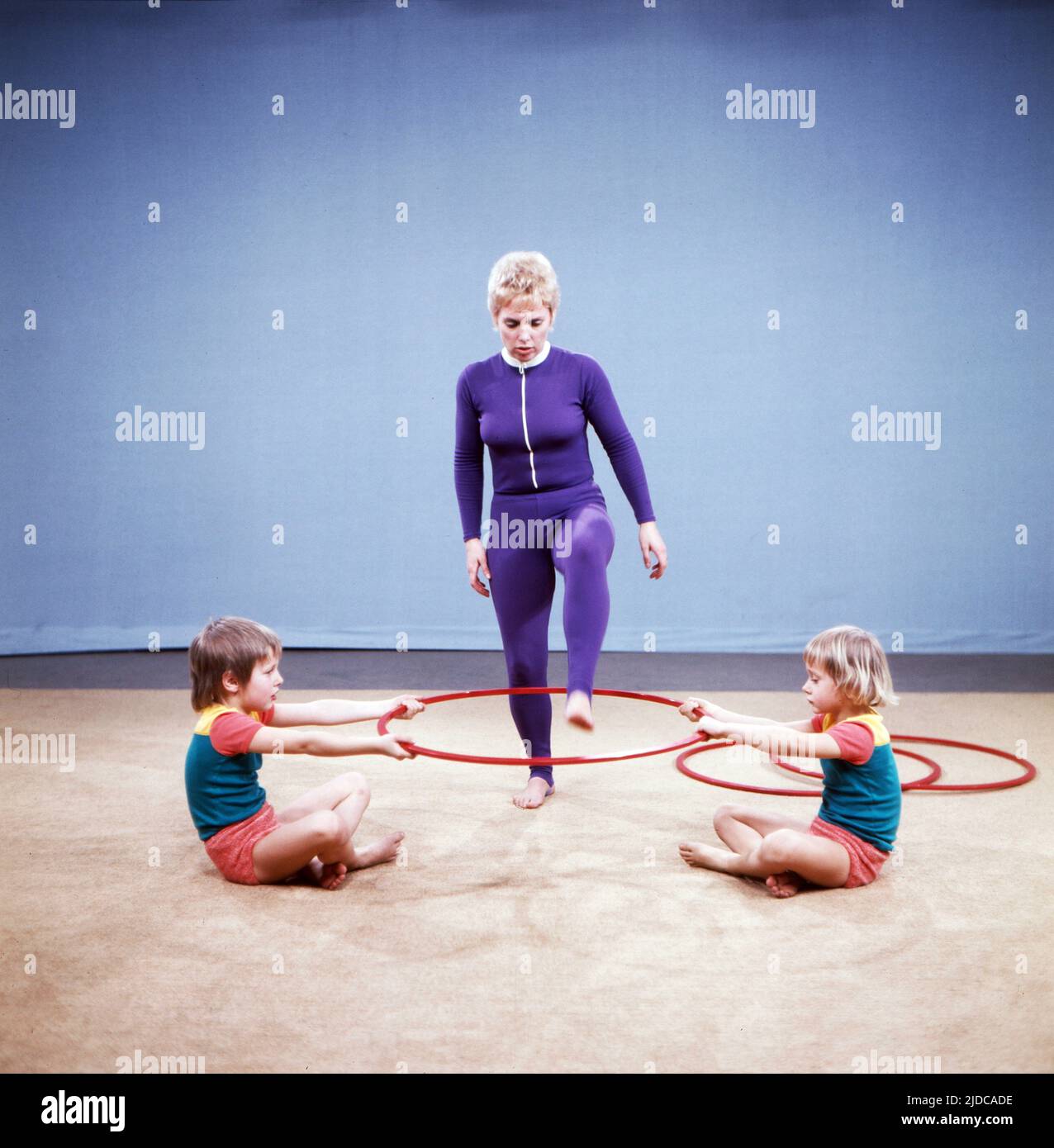 Turn mit!, Gymnastik Serie, Deutschland 1972, Vorturnerin Bärbel Vitt mit den Kindern Kathrin und Jan-Christoph turnen mit Hula Hoop Reifen Stock Photo