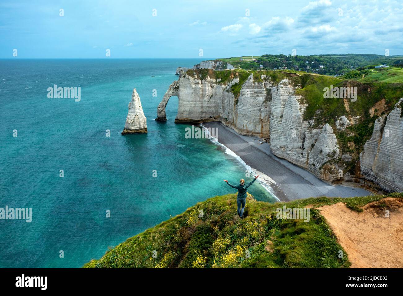 Happy young woman a cliff looking at the famous Elephant White cliffs of Etretat & the Alabaster Coast, Seine-Maritime, Normandy, France Stock Photo
