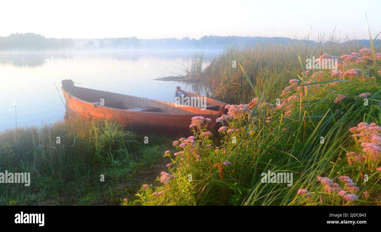 Fishing on a boat in the middle of the morning lake Stock Photo - Alamy
