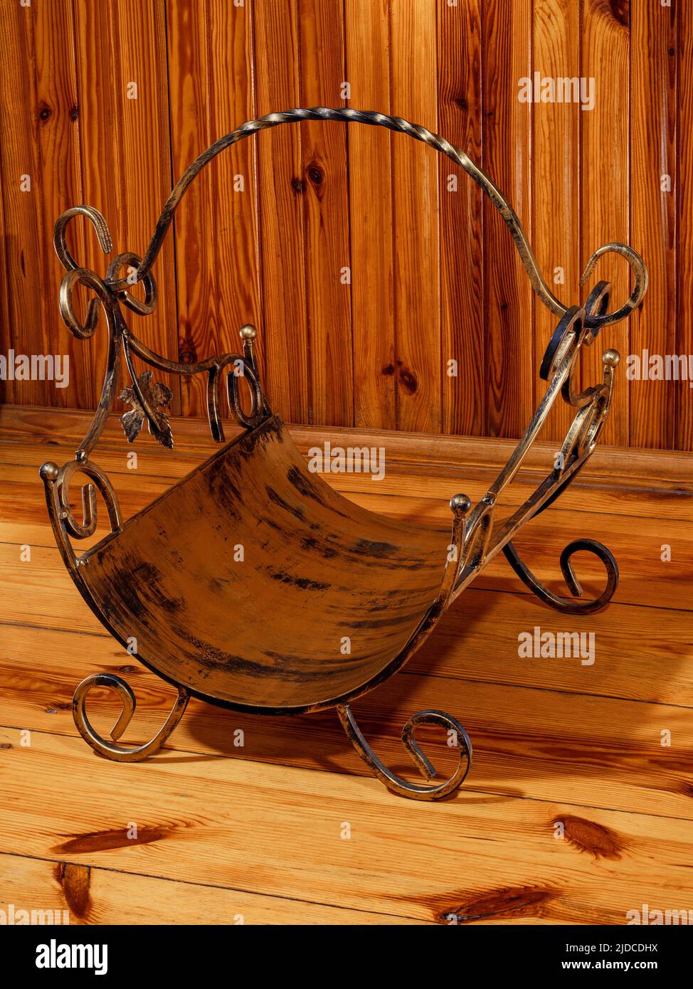 Antique empty metal firewood basket by a wooden wall Stock Photo