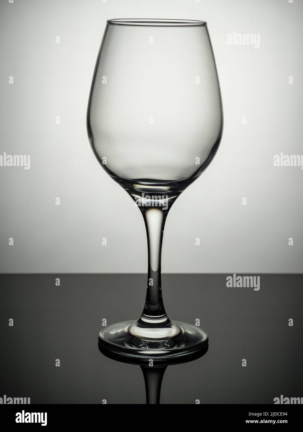 An empty wine glass stands on a grey surface Stock Photo