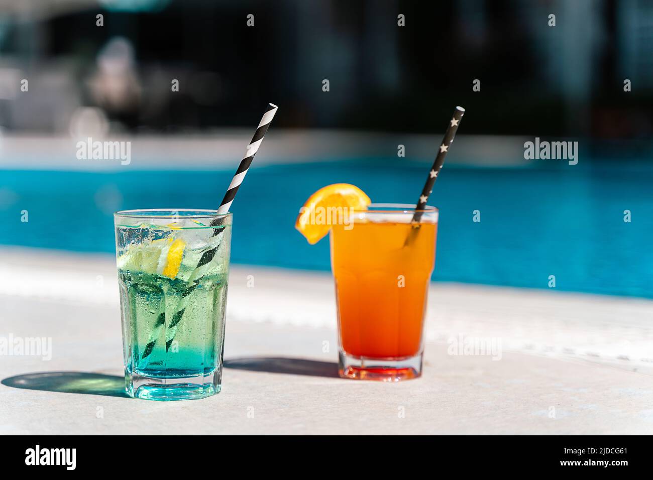 Tropical sparkling lemonade cocktails by the pool. Glasses with orange and mint lemon fruit cocktails. Summer alcohol free drink by the hotel pool Stock Photo