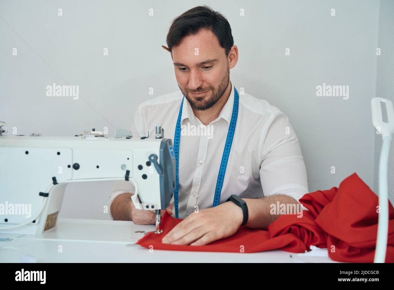 Happy fashion designer making red dress with equipment Stock Photo - Alamy