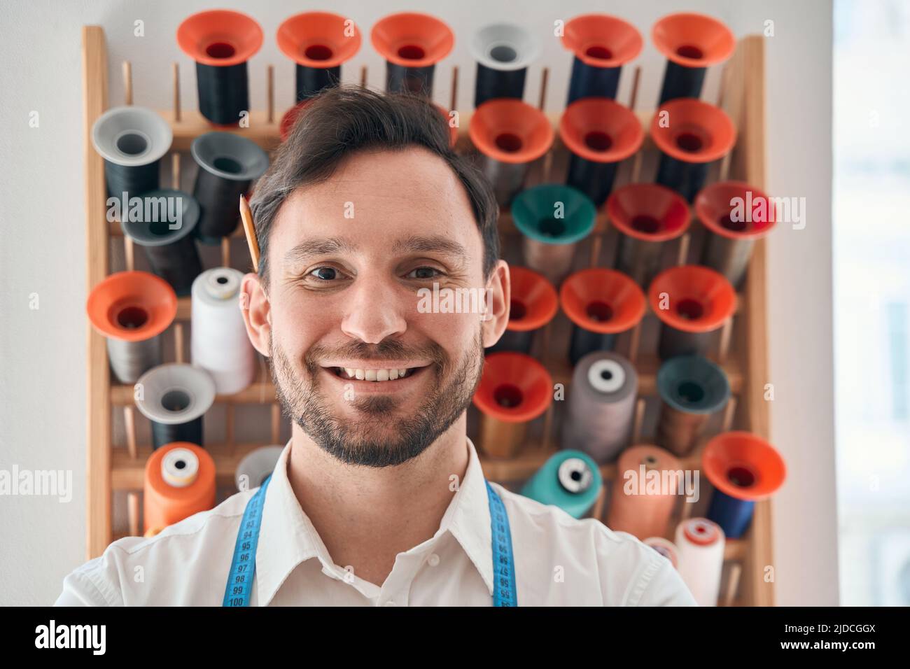 Joyful male dressmaker with spools in atelier Stock Photo Alamy