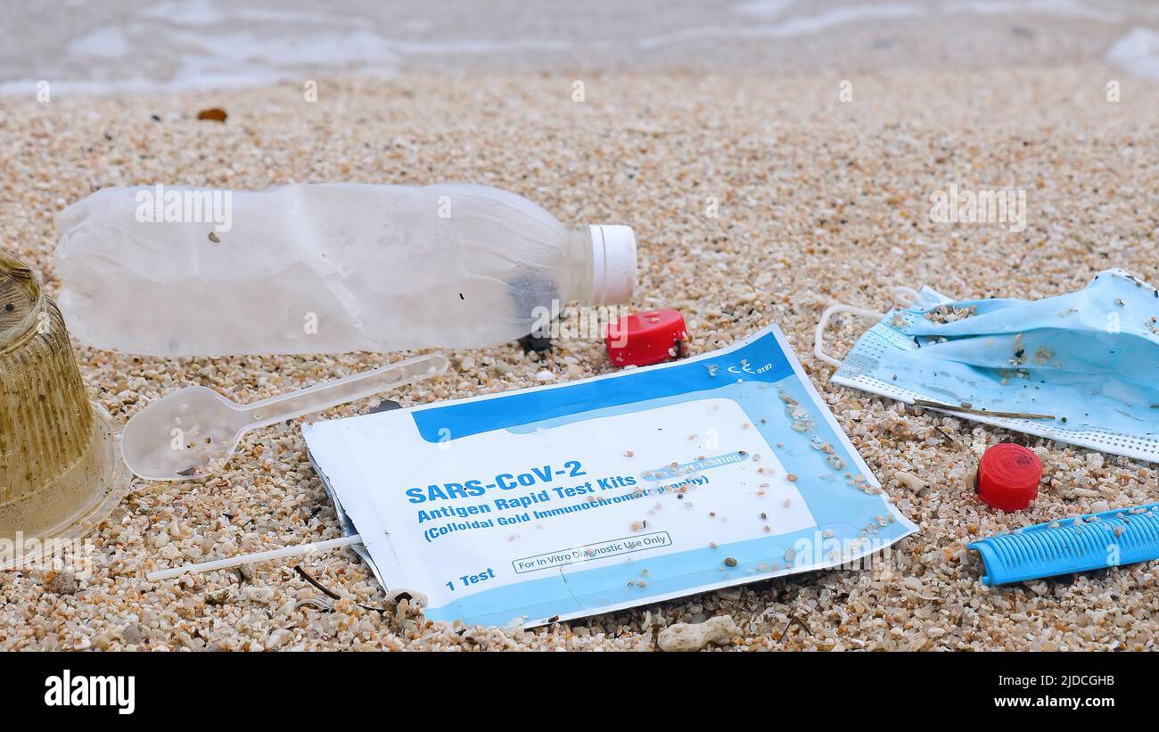 Plastic ocean pollution trash - plastic bottle, face mask, self kit test for COVID-19 on beach. Sea water pollution concept. Waste during COVID-19. Stock Photo