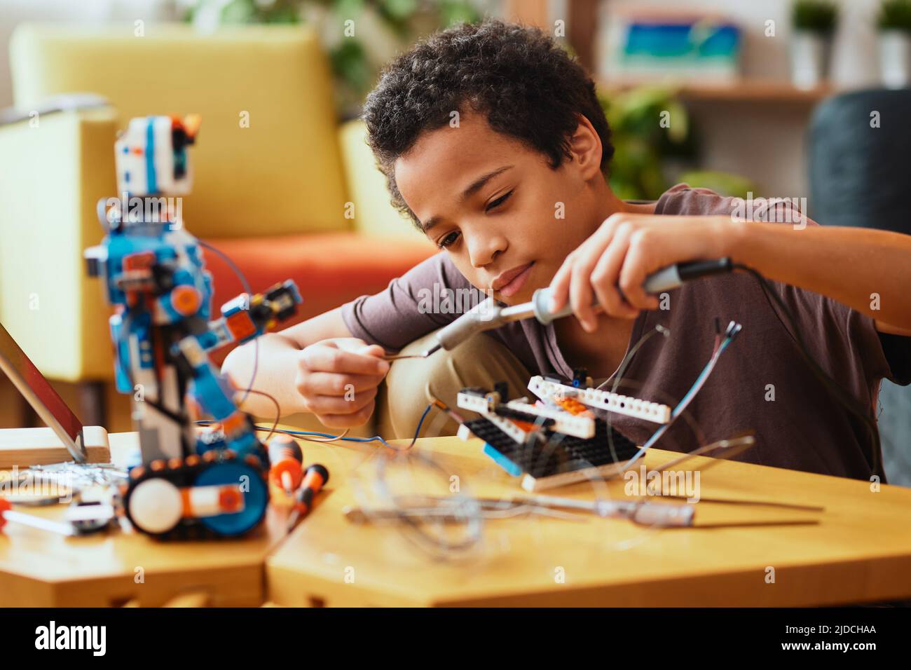 Smart African boy making a robot at home for science class. Robotics