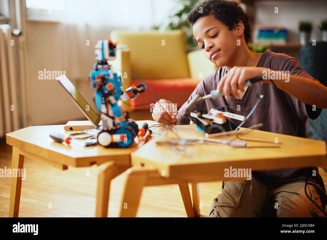 An AfricanAmerican boy making a robot at home. Education in robotic at