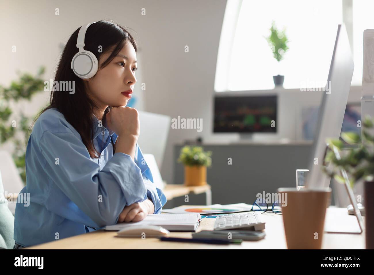 Asian Businesswoman Using Computer Working Online In Office, Side View Stock Photo