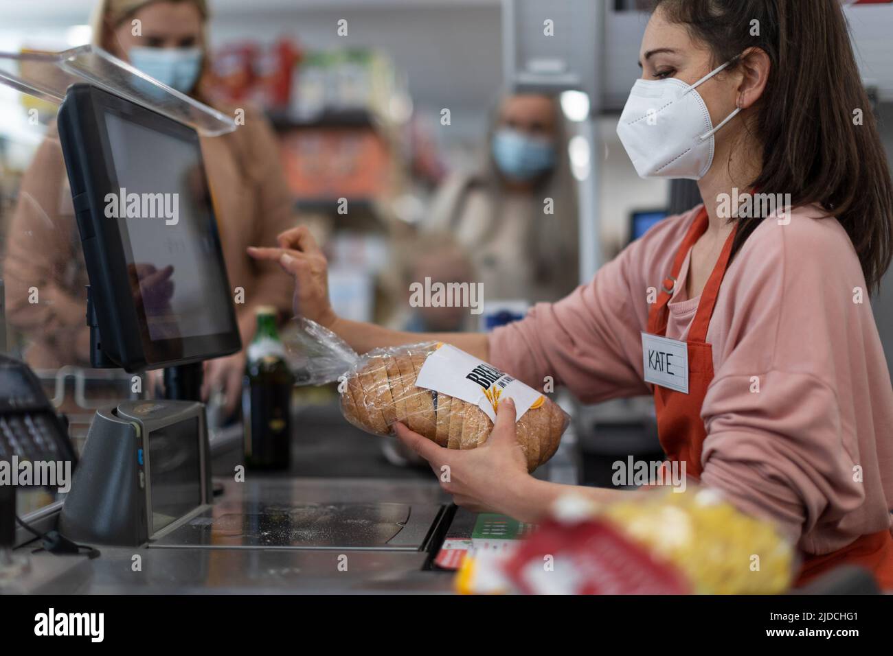 Checkout counter hands of the cashier scans groceries in supermarket, during pandemic. Stock Photo