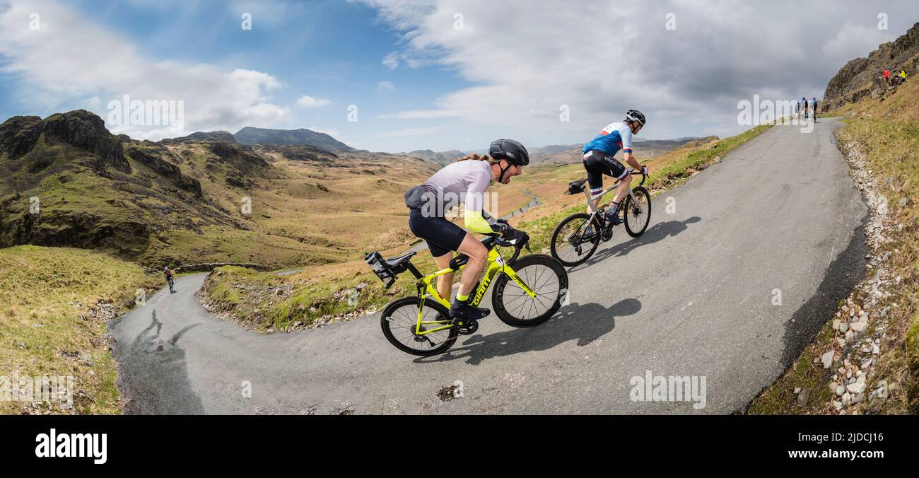 Two cyclists riding fast up Hardknott Pass in the Fred Whitton Challenge cycling sportive held in the English Lake District, UK. Stock Photo