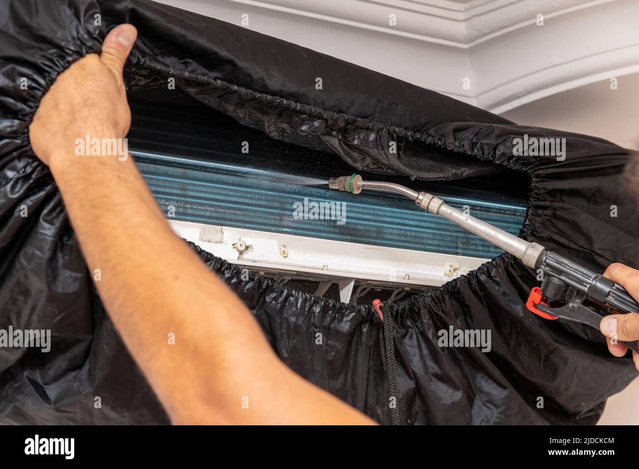 Technician cleans the air conditioner by spraying water and chemicals