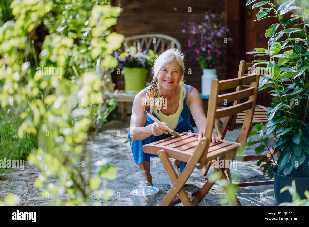 Senior woman cleaning and renovating garden furniture and getting the
