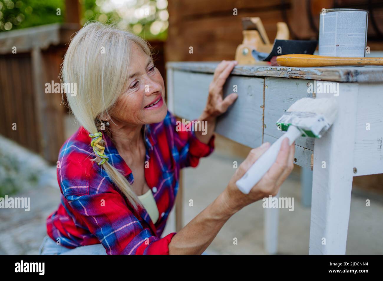 Senior woman cleaning and renovating garden furniture and getting the garden ready for summer Stock Photo