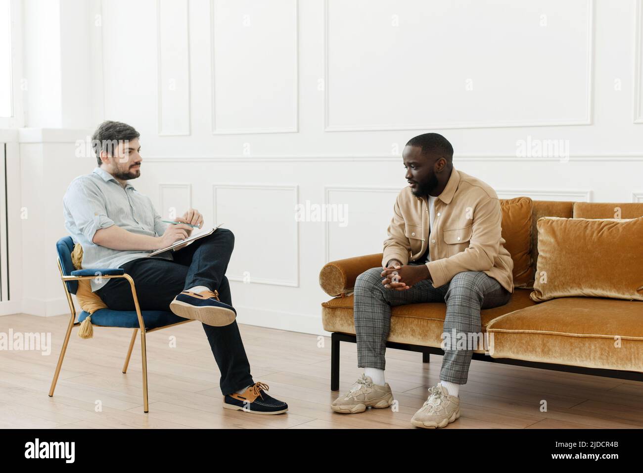 The therapist takes notes while talking to a depressed male patient and ...