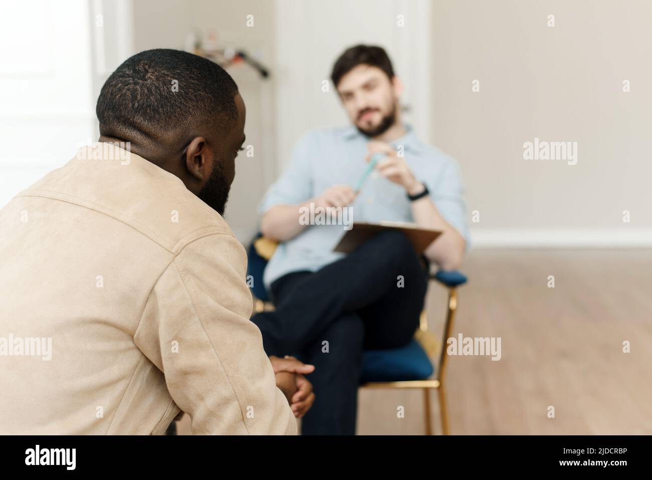 Unhappy young black man having session with professional psychologist at mental health clinic. Professional psychological help concept. Stock Photo