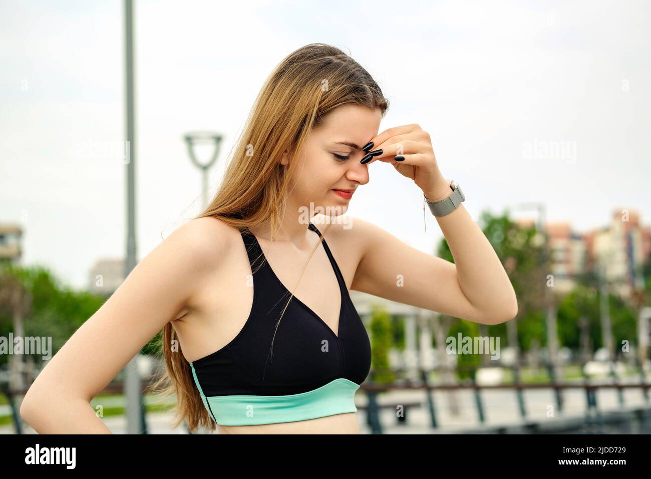 Beautiful woman wearing sports bra standing on city park