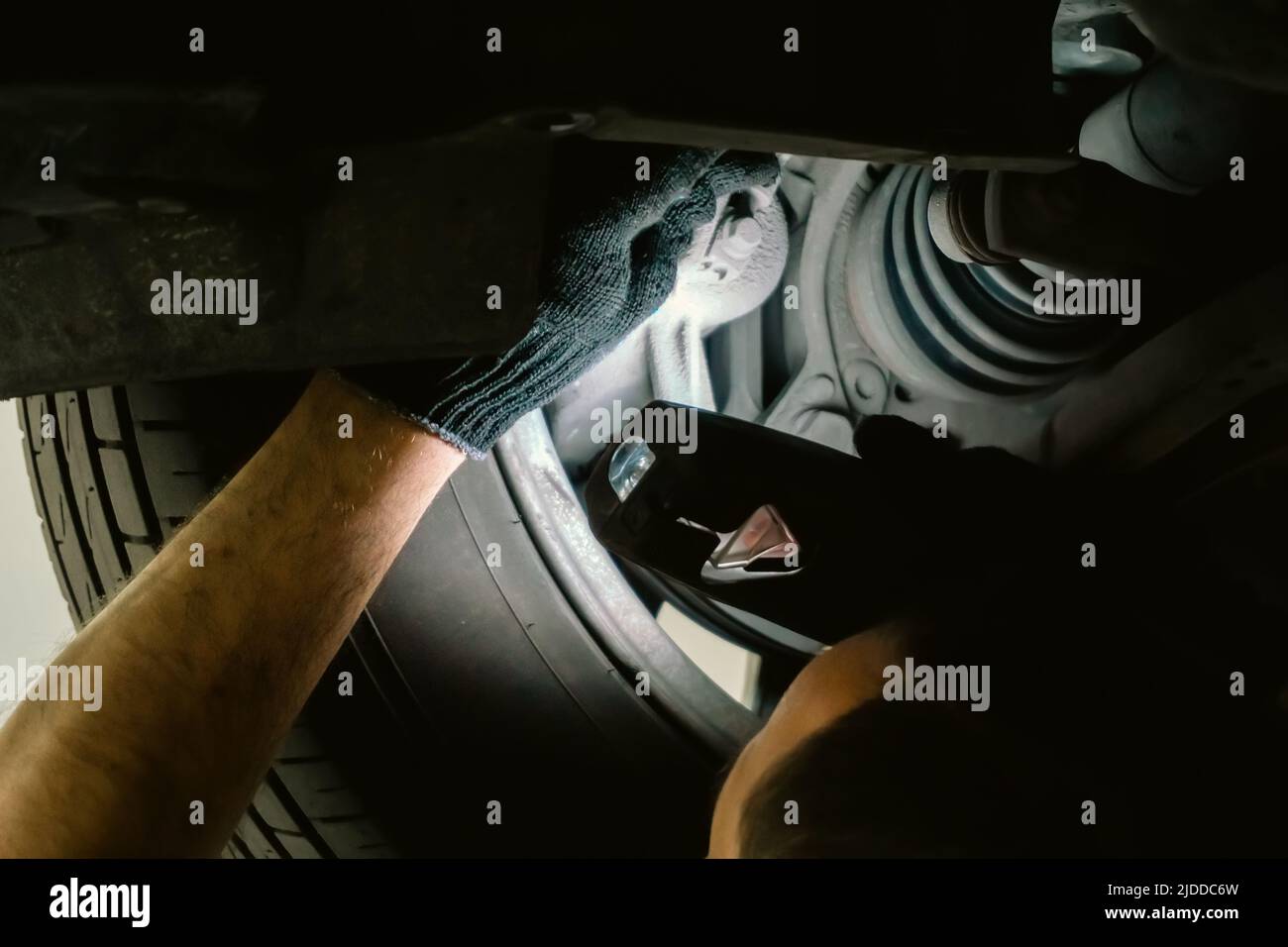 Serviceman inspects wheels and chassis of car, troubleshooting and