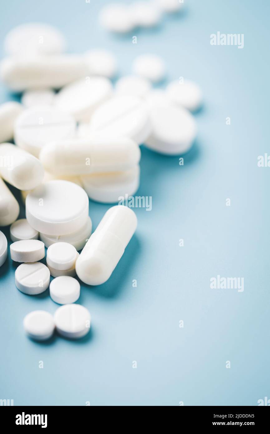 Various white pills on blue background. Stock Photo
