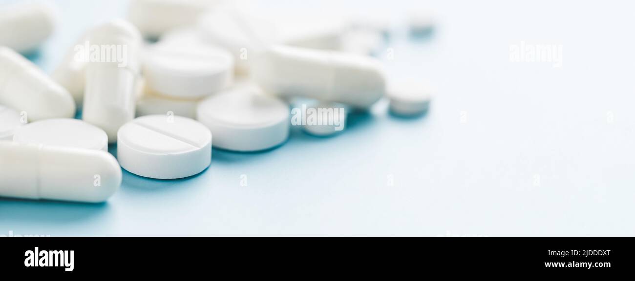 Banner with various white pills on blue background. Stock Photo