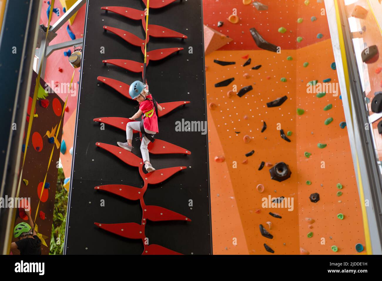 Child climbing on wall in amusement centre. Climbing training for