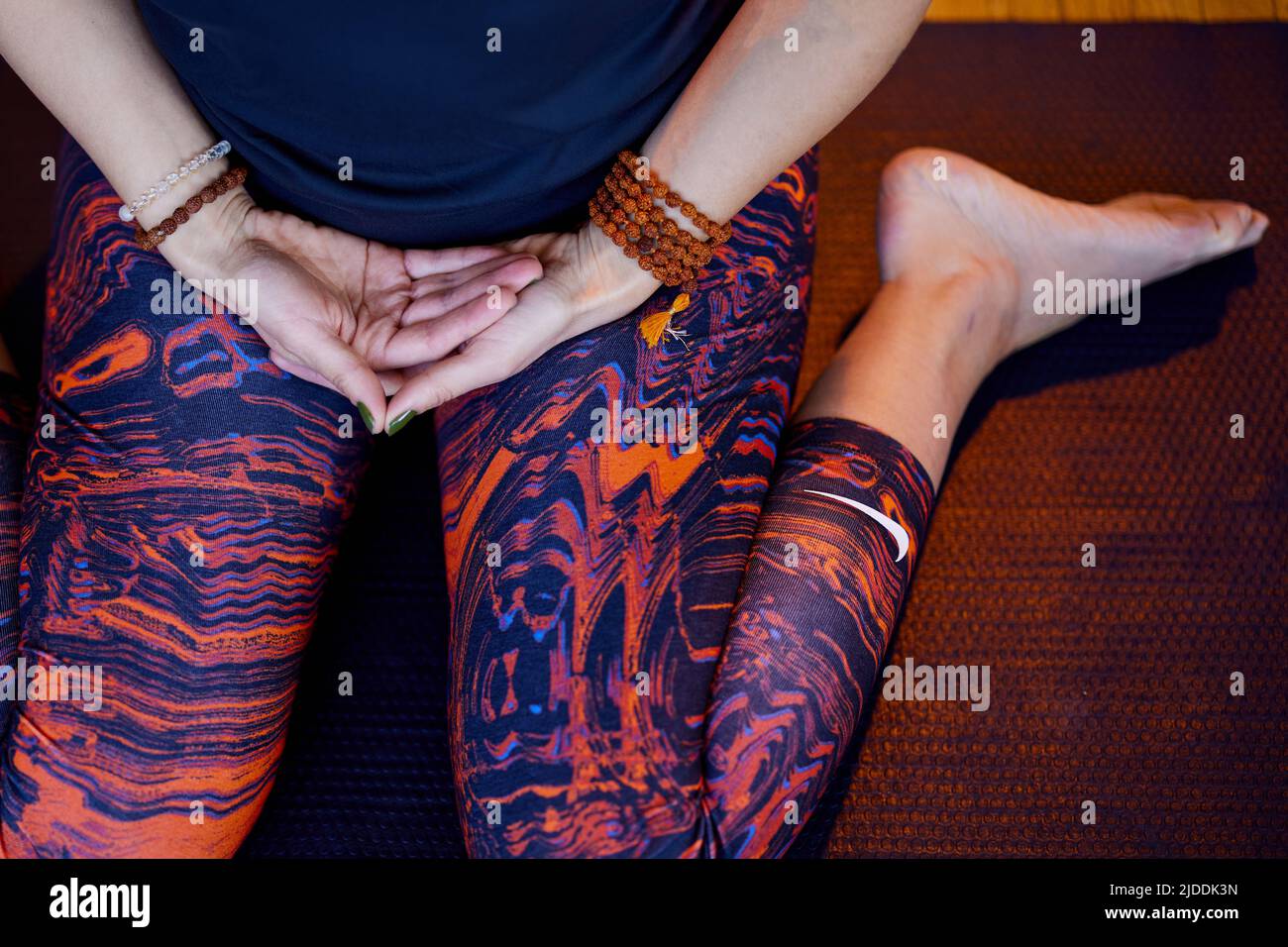 A calm woman sitting on yoga mat at home and meditating in hero posture. Stock Photo