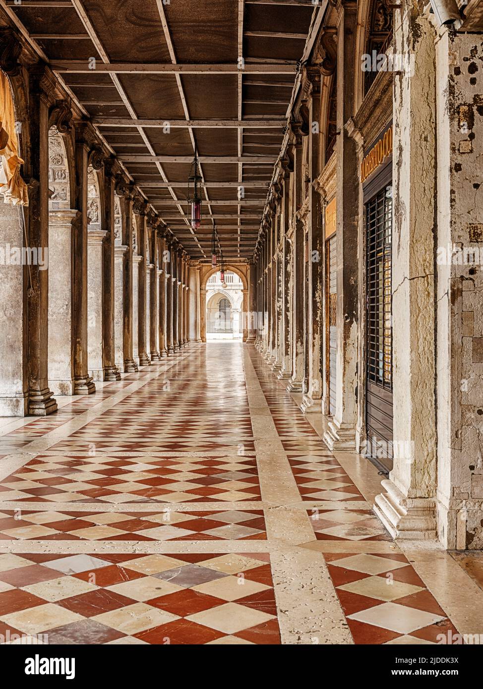 A long passage next to the Doge's Palace in Venice is covered in marble tiles between stone columns. Stock Photo