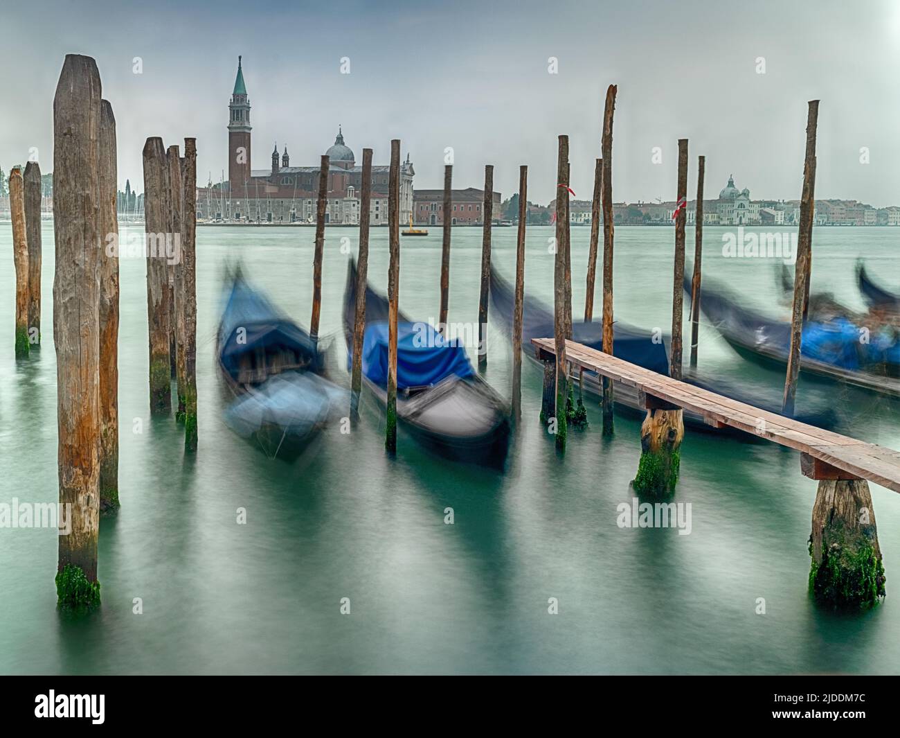 Gondolas move around with the motion of the water while they are moored on the Grand Canal of Venice. Stock Photo