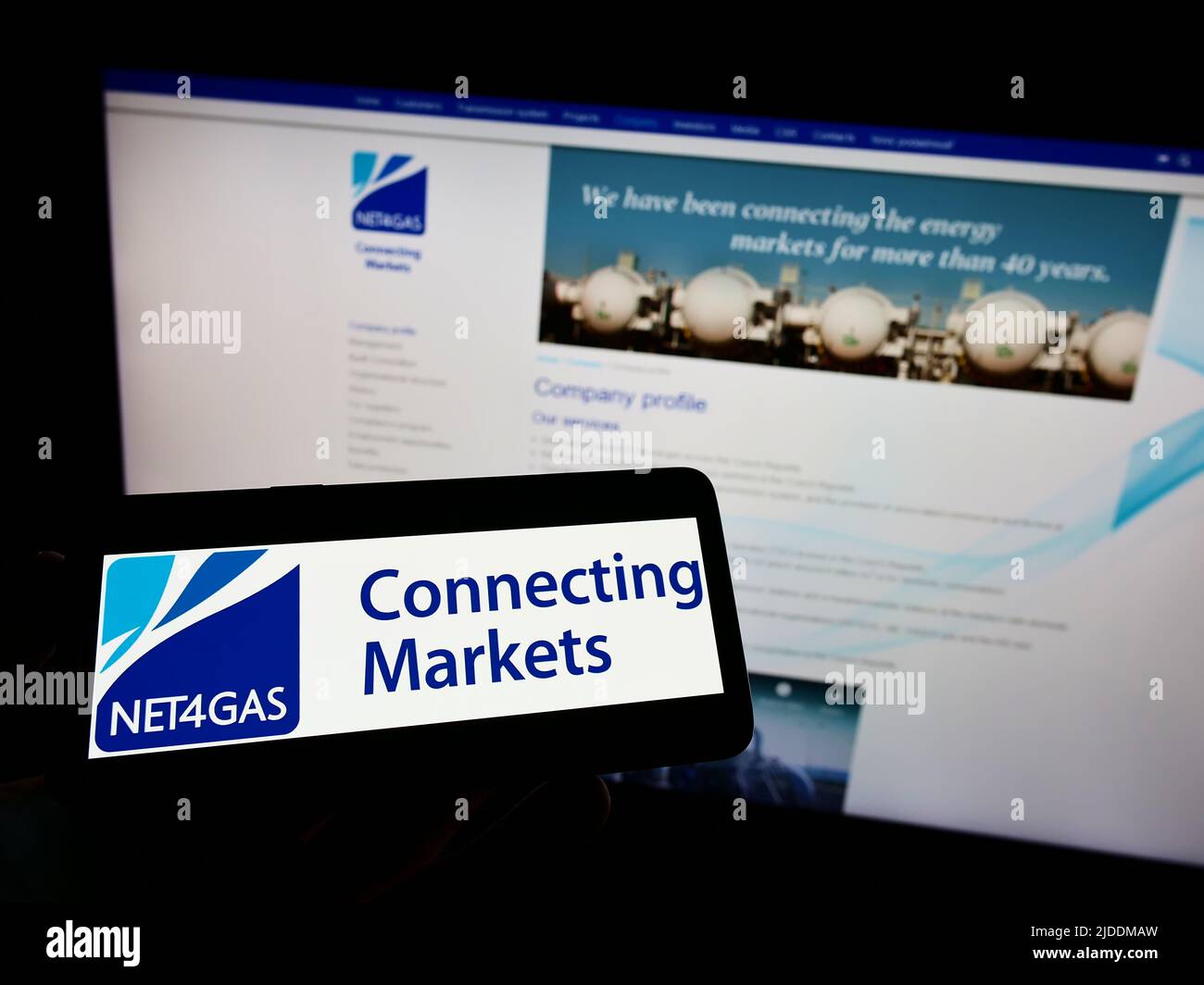 Person holding mobile phone with logo of Czech gas transmission company NET4GAS s.r.o. on screen in front of web page. Focus on phone display. Stock Photo