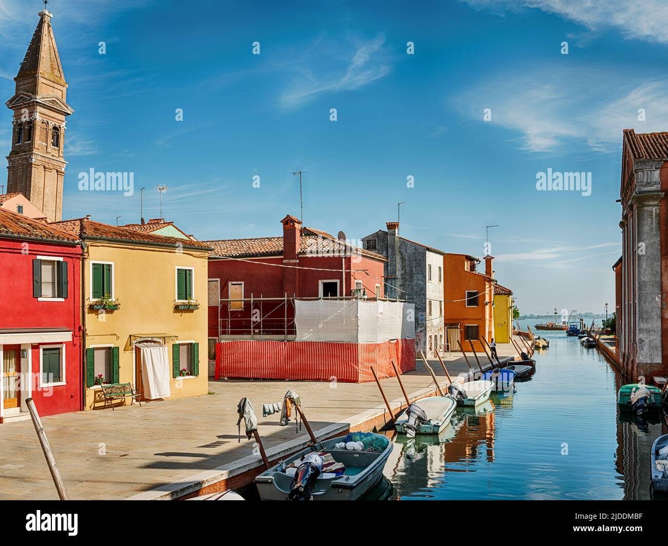 Sunlight illuminates one side of a canal in the town of Burano in the Venice harbor. Stock Photo