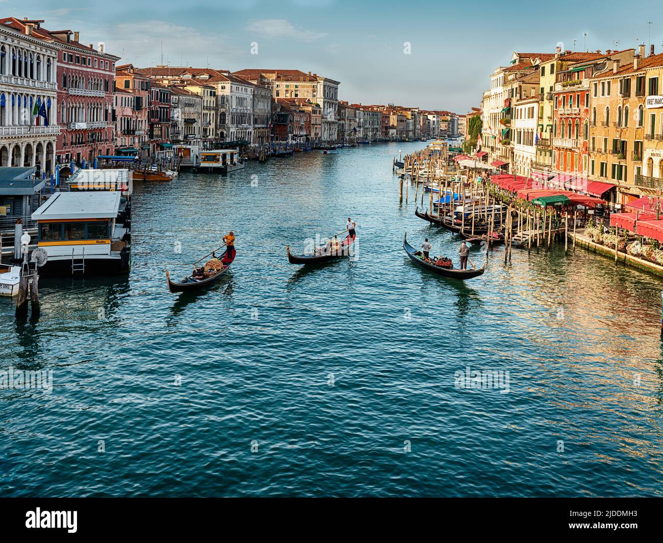 Three gondolas travel on the Grand Canal in Venice as seen from the Rialto Bridge early on a sunny morning. Stock Photo