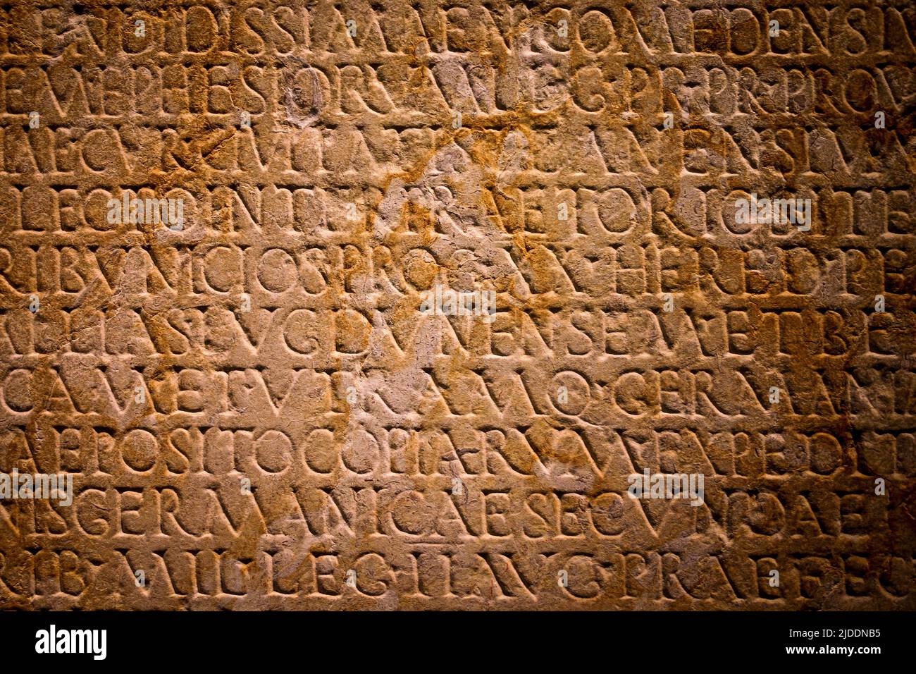 Latin text written in stone. Full frame Roman text carved into a flat stone wall. Stock Photo