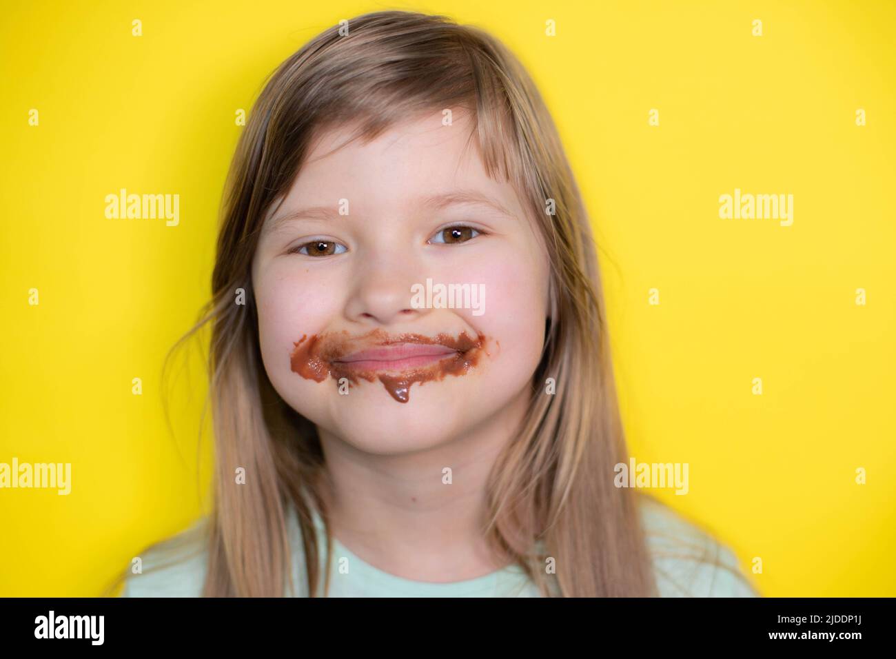 Laughing little girl eating chocolate dirty face Stock Photo