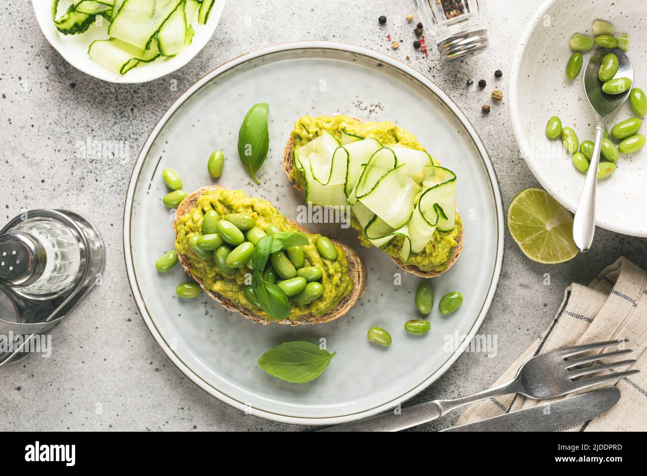 Healthy avocado toasts with different toppings edamame beans, cucumber, basil and seeds. Top view, toned image Stock Photo