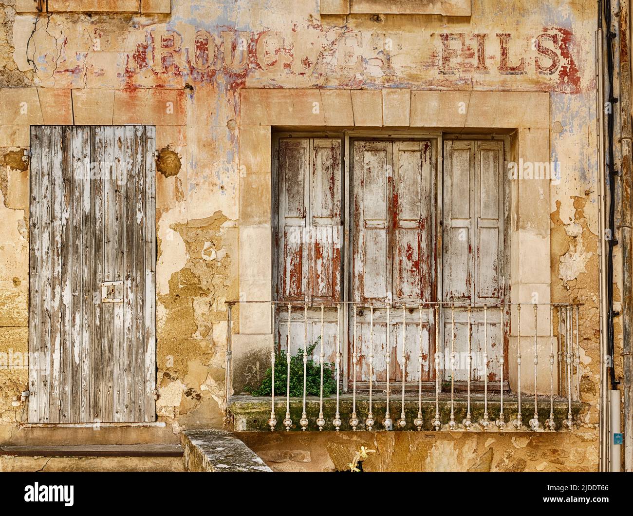 An old shop window with faded red lettering is closed in the town of Menerbes in the Luberon area of France. Stock Photo