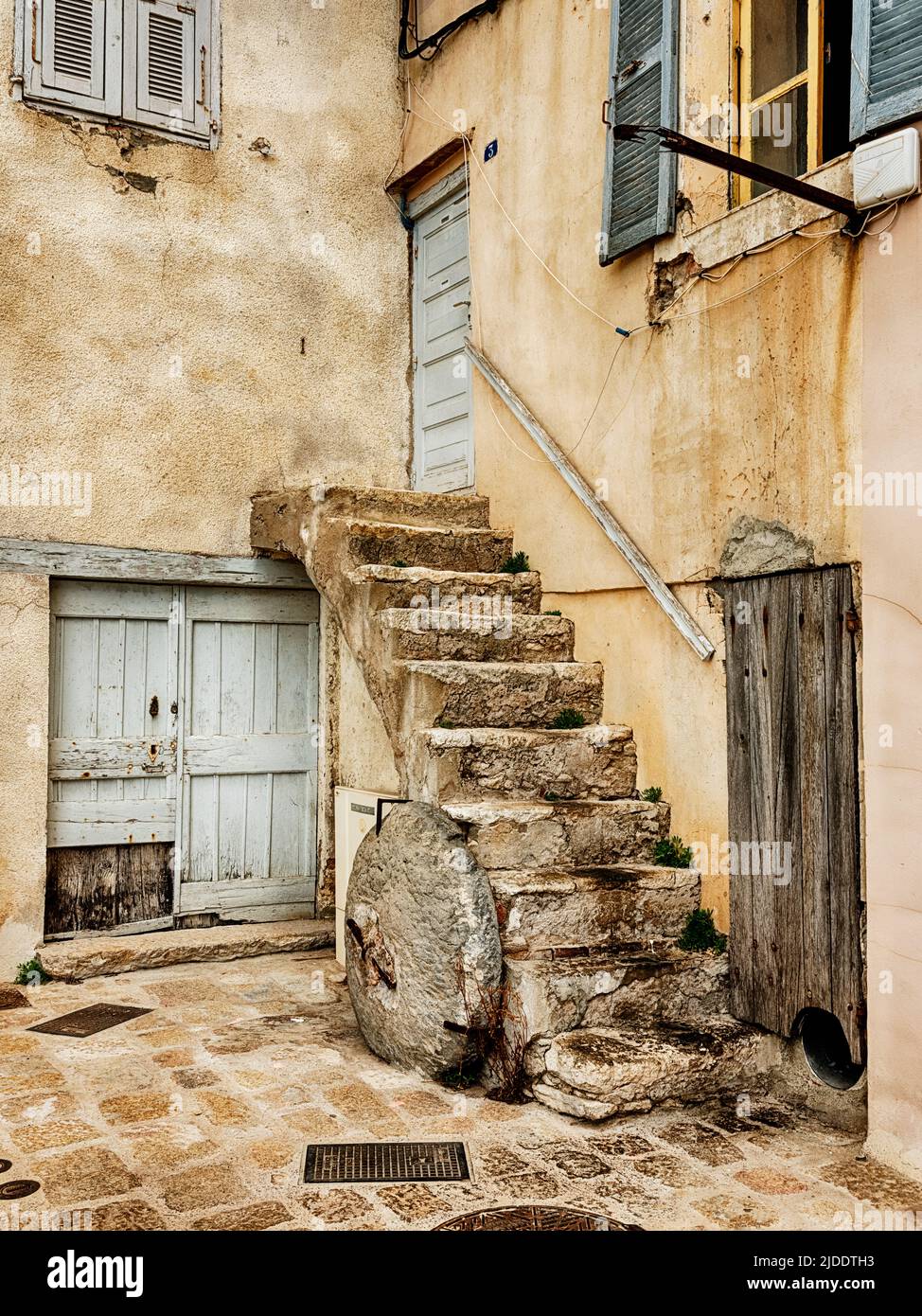 A quiet courtyard in Bonifacio just off the main street includes a set of stairs to a second floor doorway. Stock Photo